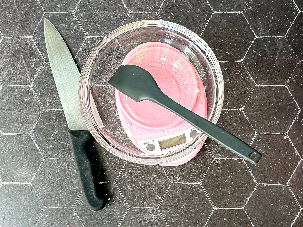 Biscuit making tools on a sheet pan on a black tile background.