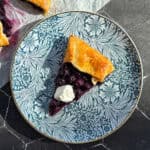 Slice of blueberry galette on a blue floral plate.