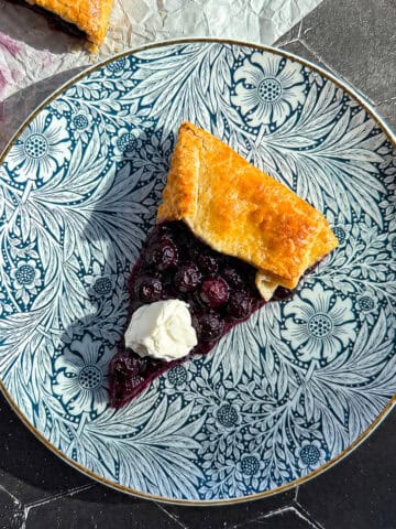 Slice of blueberry galette on a blue floral plate.