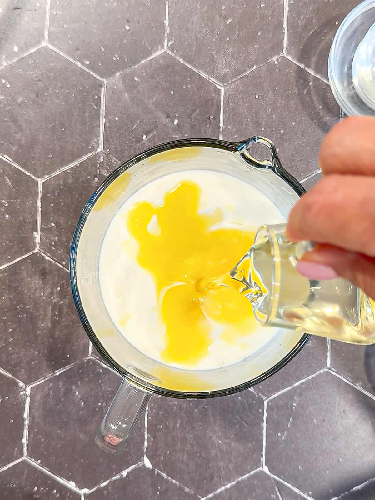 Pouring melted butter and milk into wet ingredients for waffle batter.