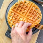 Lifting a cornmeal waffle out of a waffle maker.