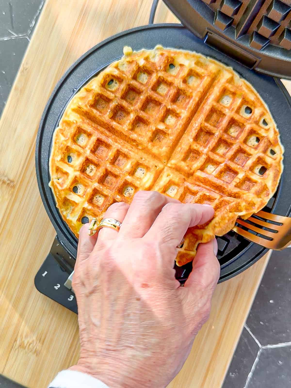 Lifting a cornmeal waffle out of a waffle maker.