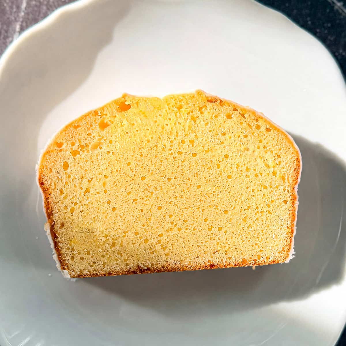 A slice of lemon loaf cake on a white plate.