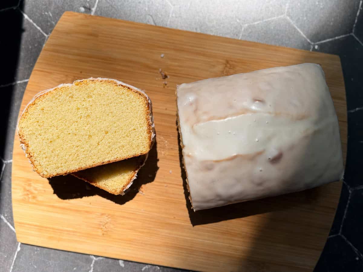 Lemon loaf cake, some slice slices to the side, on a wooden cutting board.