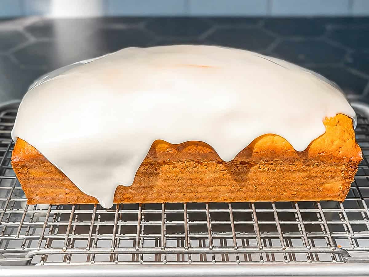 Lemming glaze dripping over the sides of a lemon loaf cake on a wire rack.