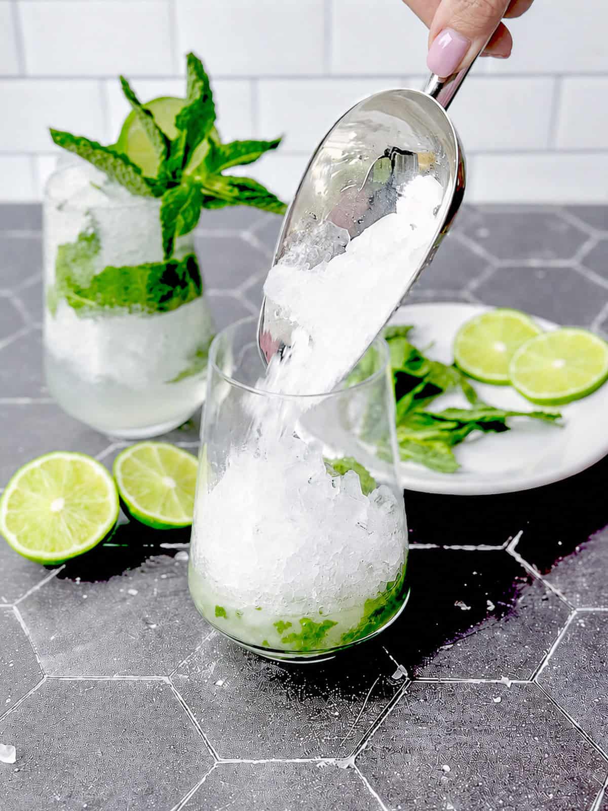 Adding crushed ice to a mocktail in a cocktail glass.