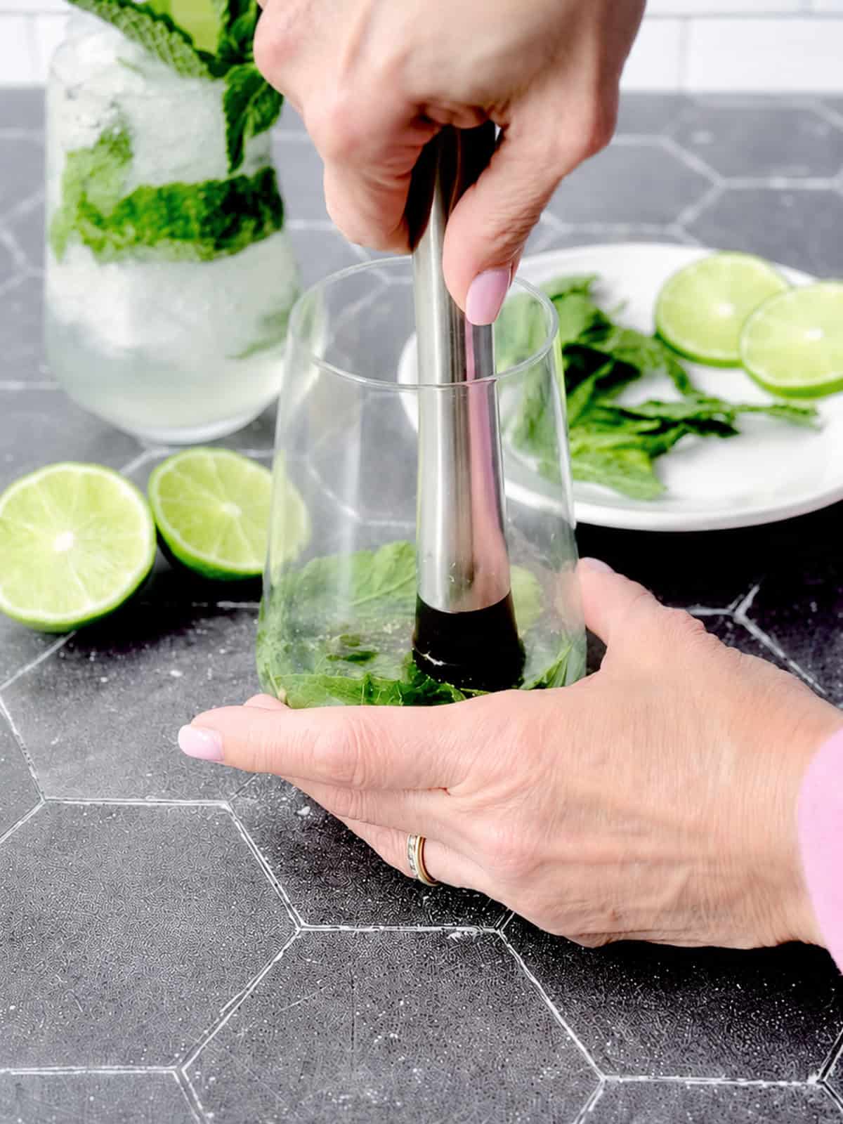Muddling mint in a cocktail glass.