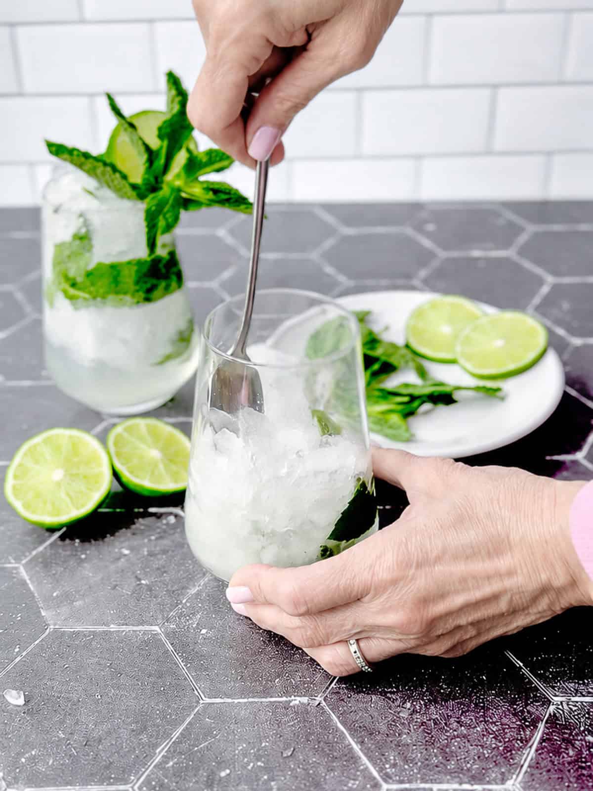 Stirring liquid ingredients with crushed ice in a cocktail glass.