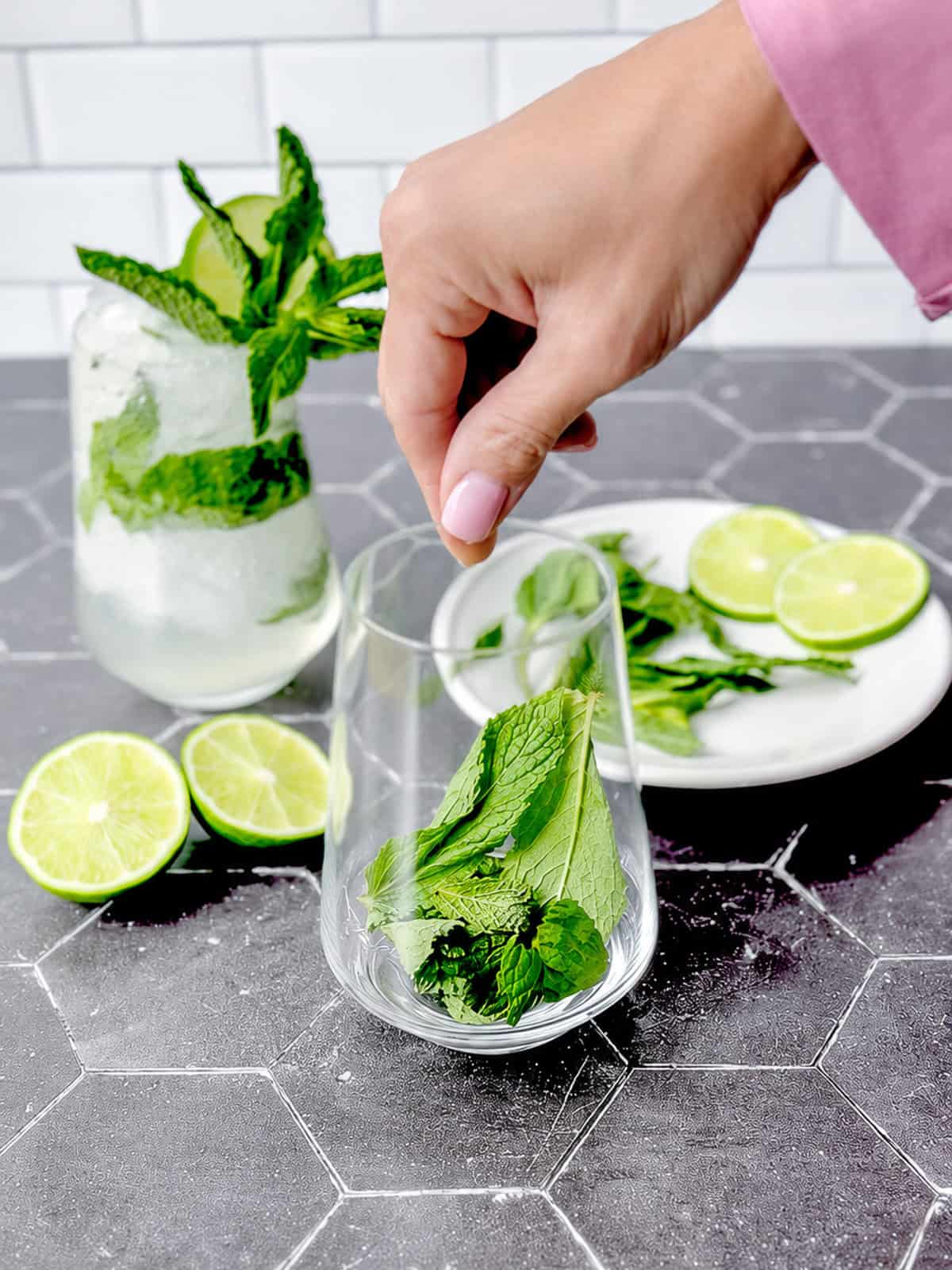 Adding Mint leaves to a cocktail glass.