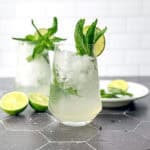 Mint julep mocktails and cocktail glasses on a black tile counter.
