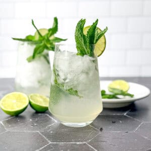 Mint julep mocktails and cocktail glasses on a black tile counter.