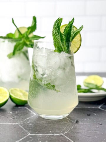 Mint julep mocktails and cocktail glasses on a black tile counter.