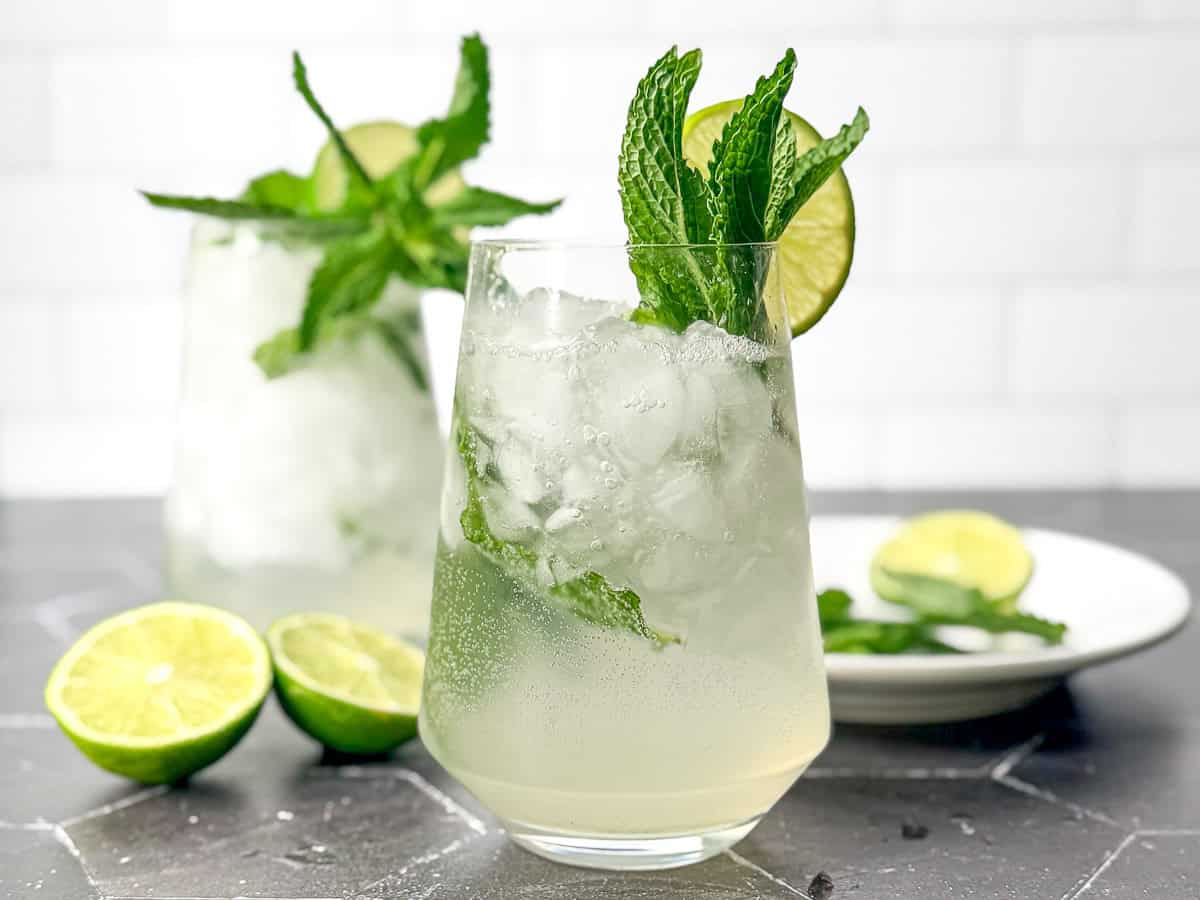 Mint julep mocktails and cocktail glasses on a black tile counter.