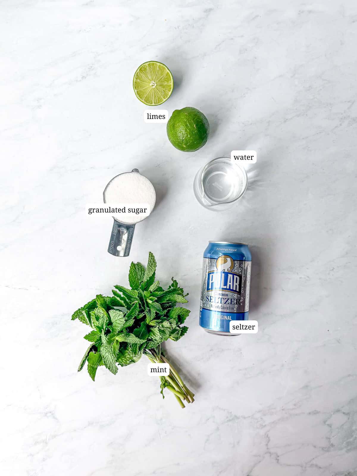 Ingredients needed to make a mint julep mocktail on a white counter.
