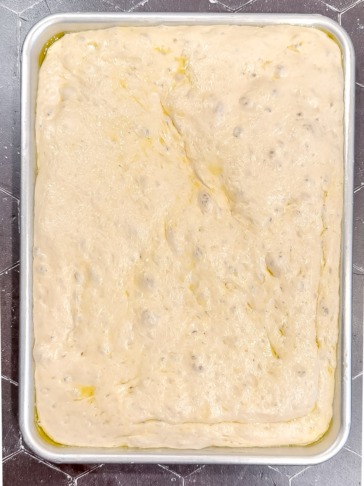 Fully risen focaccia in a small sheet pan.