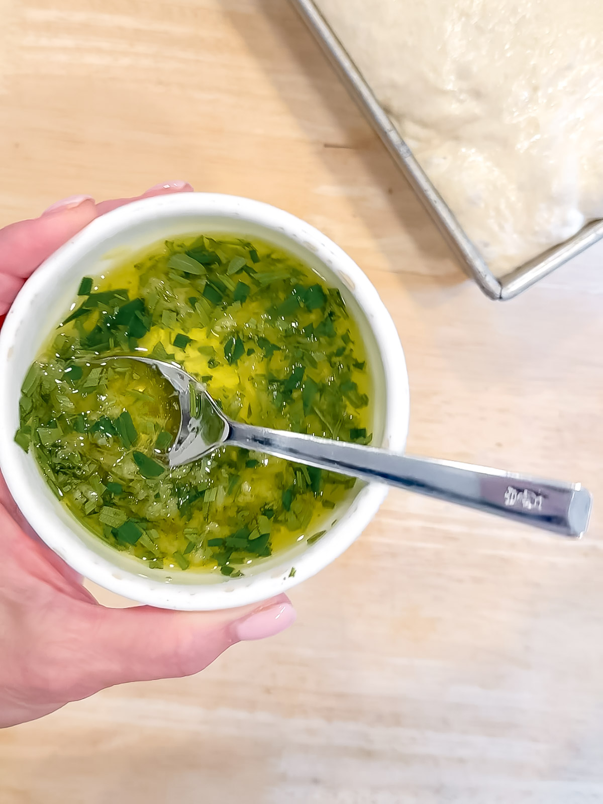 Focaccia topping in a white bowl with a spoon.