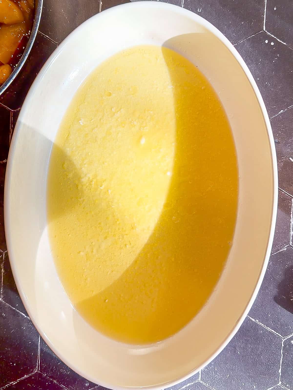 Melted butter in an oval baking dish.
