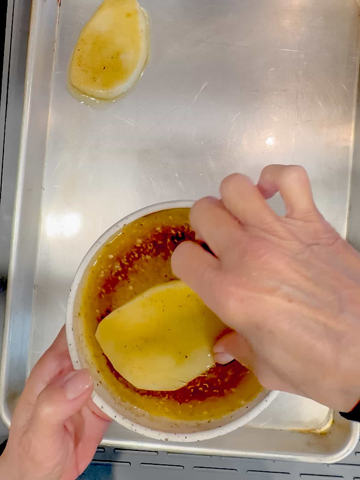 Dipping accordion potatoes in a butter and spice mixture.
