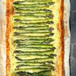 Asparagus puff pastry tart on parchment paper.
