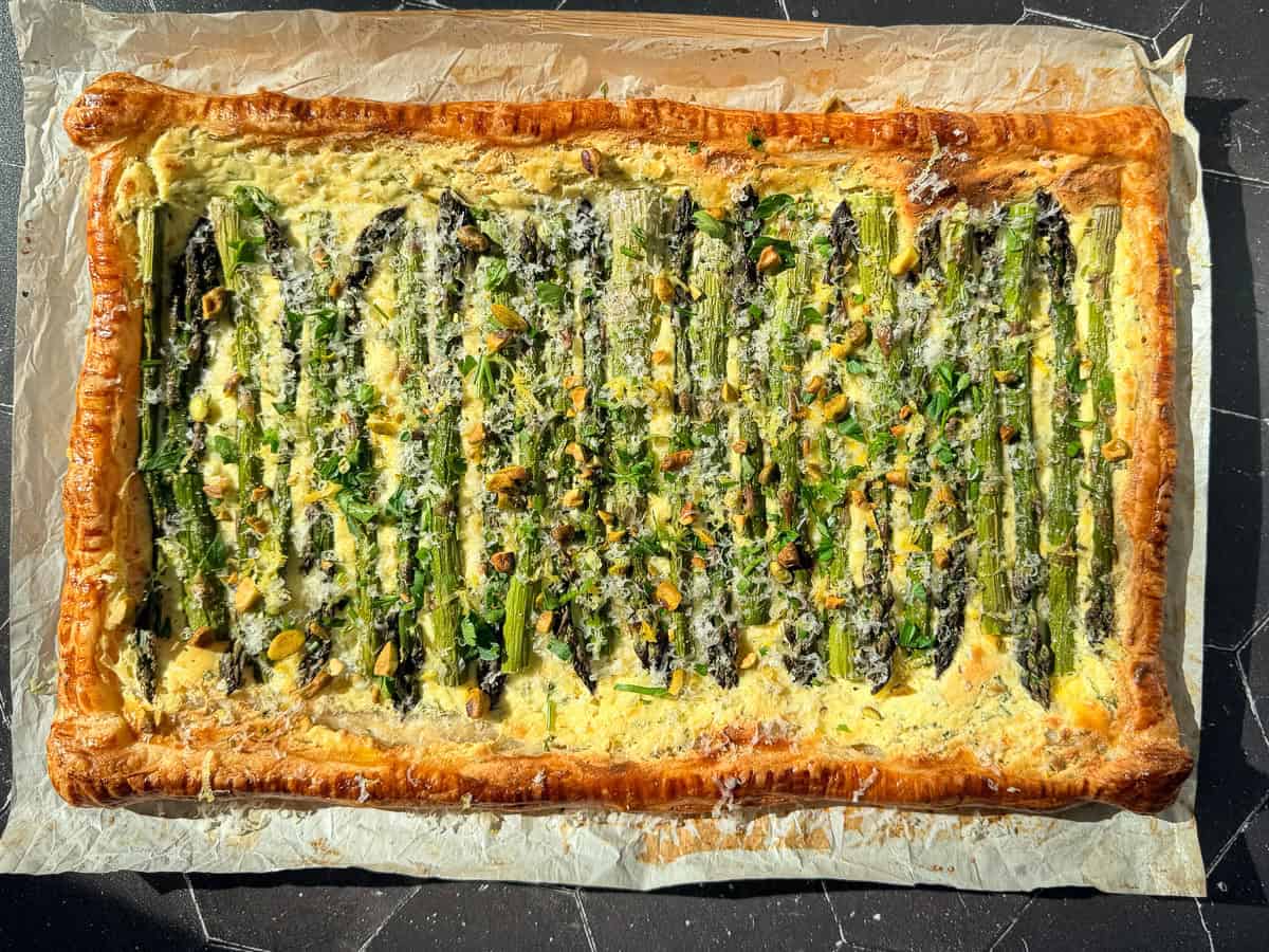 Asparagus puff pastry tart on parchment paper.