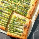 Asparagus puff pastry tart on parchment paper.