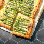 Asparagus puff pastry tart on parchment paper.