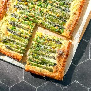 Asparagus puff pastry tart on parchment paper.