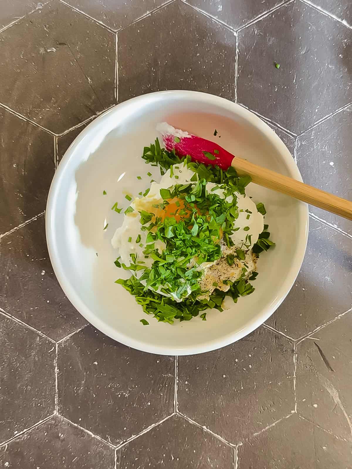 Ingredients for ricotta filling with herbs in a white bowl.