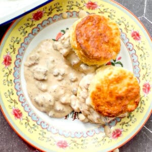 Biscuits and gravy on a yellow floral plate.
