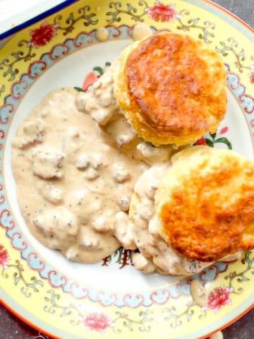 Biscuits and gravy on a yellow floral plate.