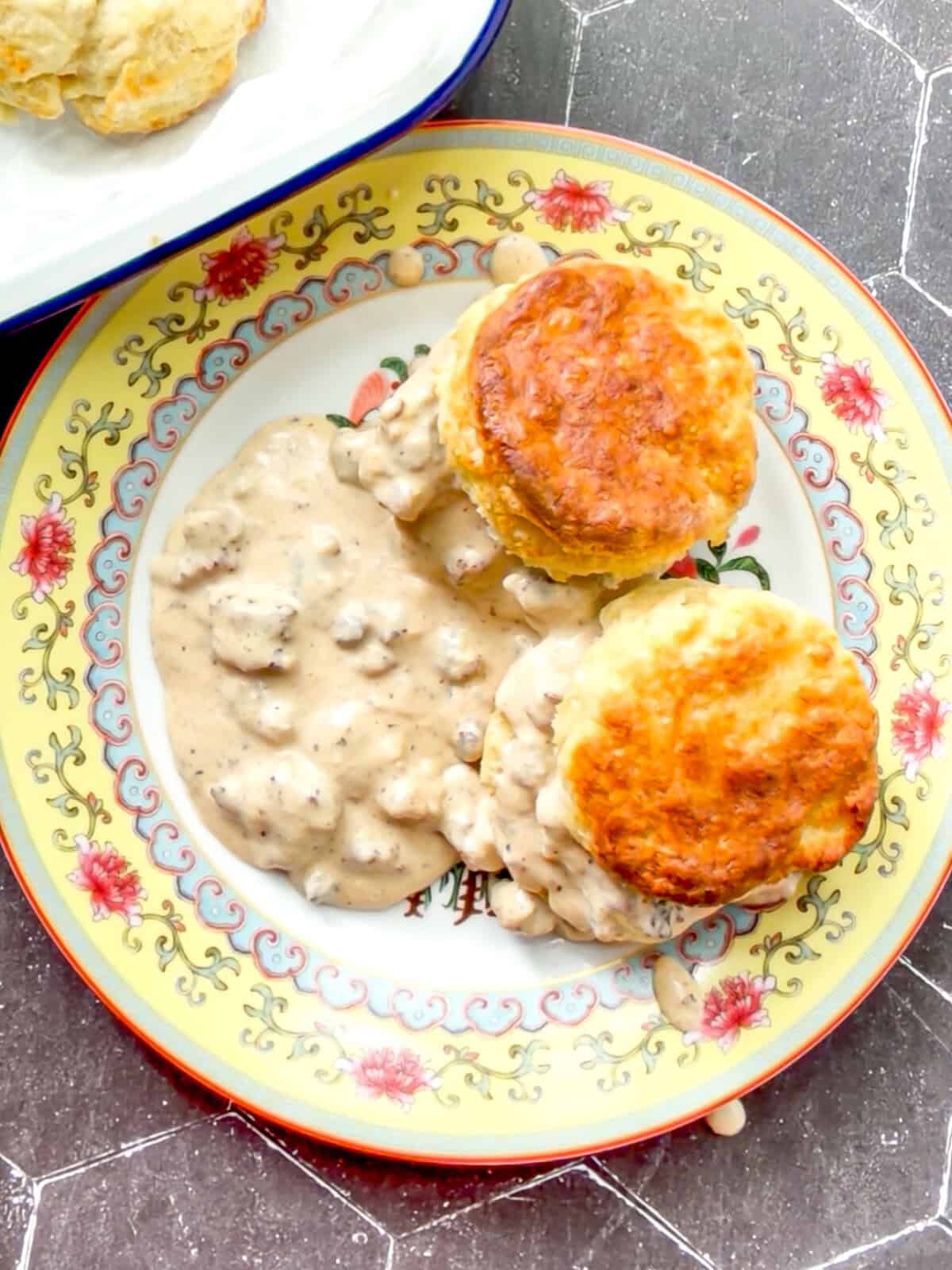 Biscuits and gravy on a yellow floral plate.