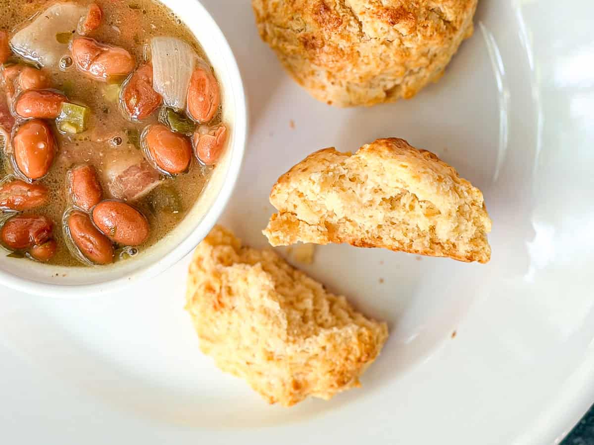 Cornbread biscuits next to a bowl of beans.