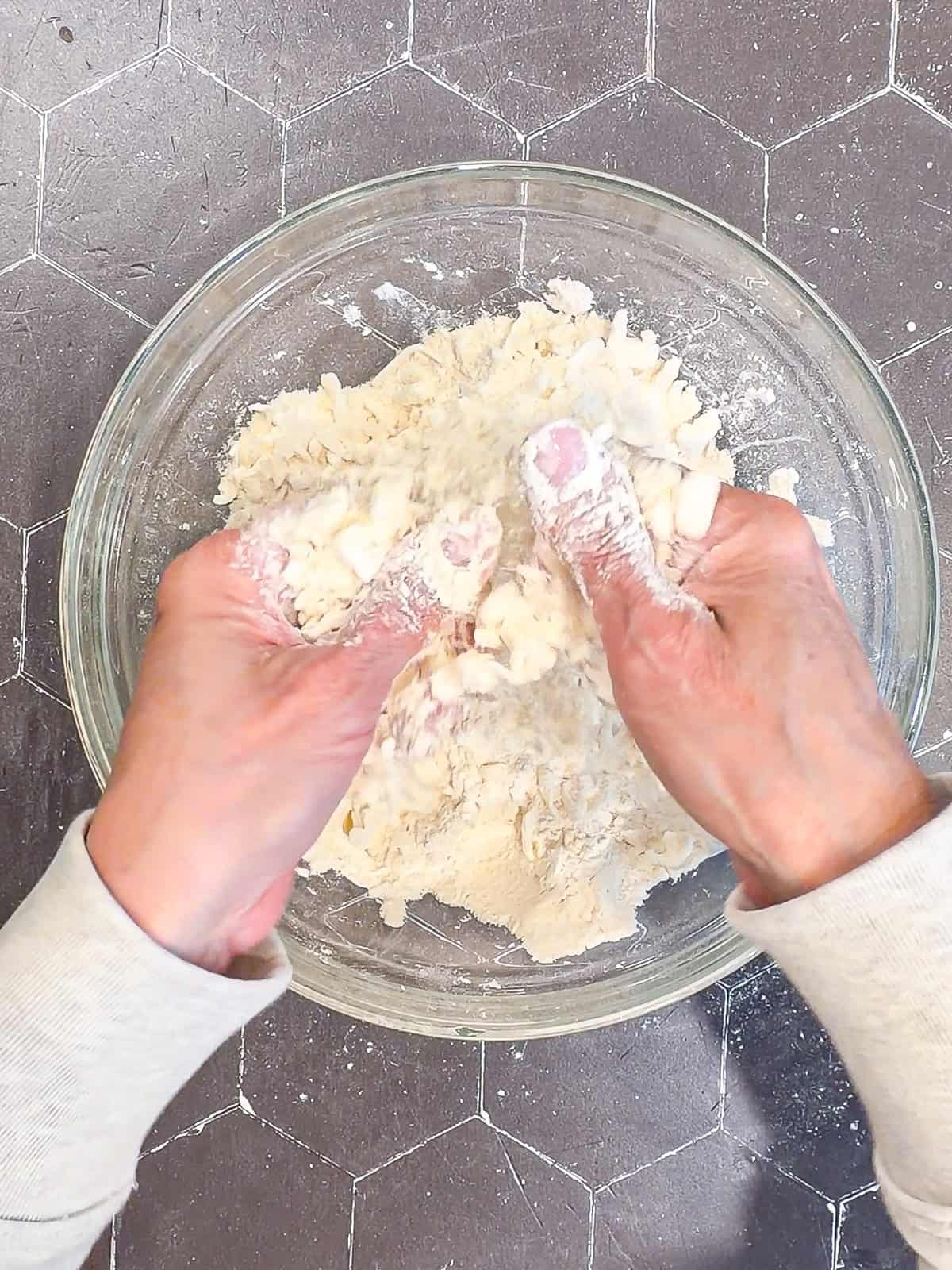 Using fingers to rub cold butter into dry biscuit ingredients.