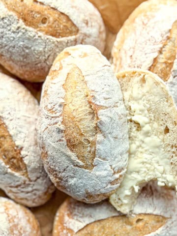 Crusty roll,s one sliced open and smeared with softened butter.