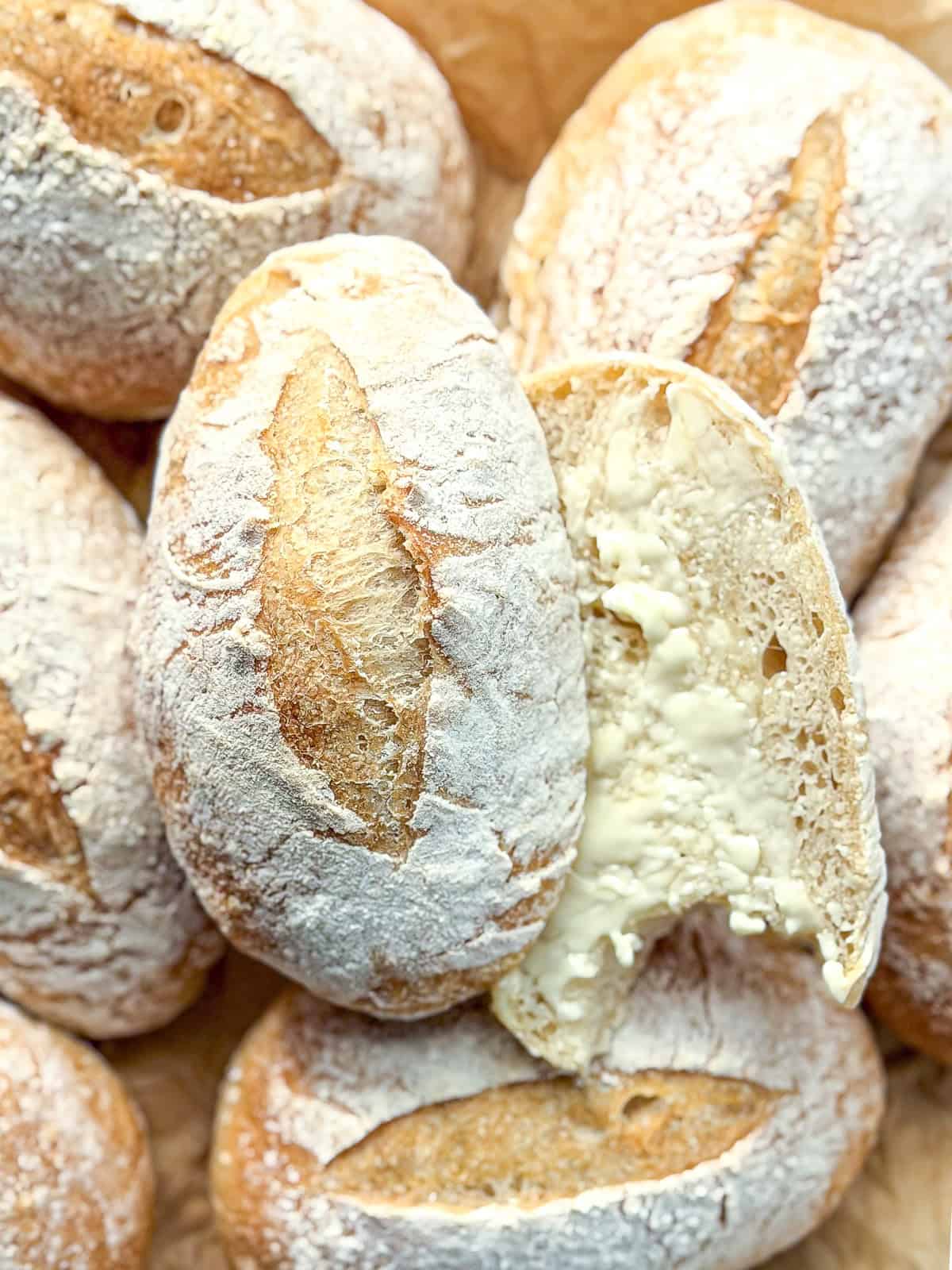 Crusty roll,s one sliced open and smeared with softened butter.
