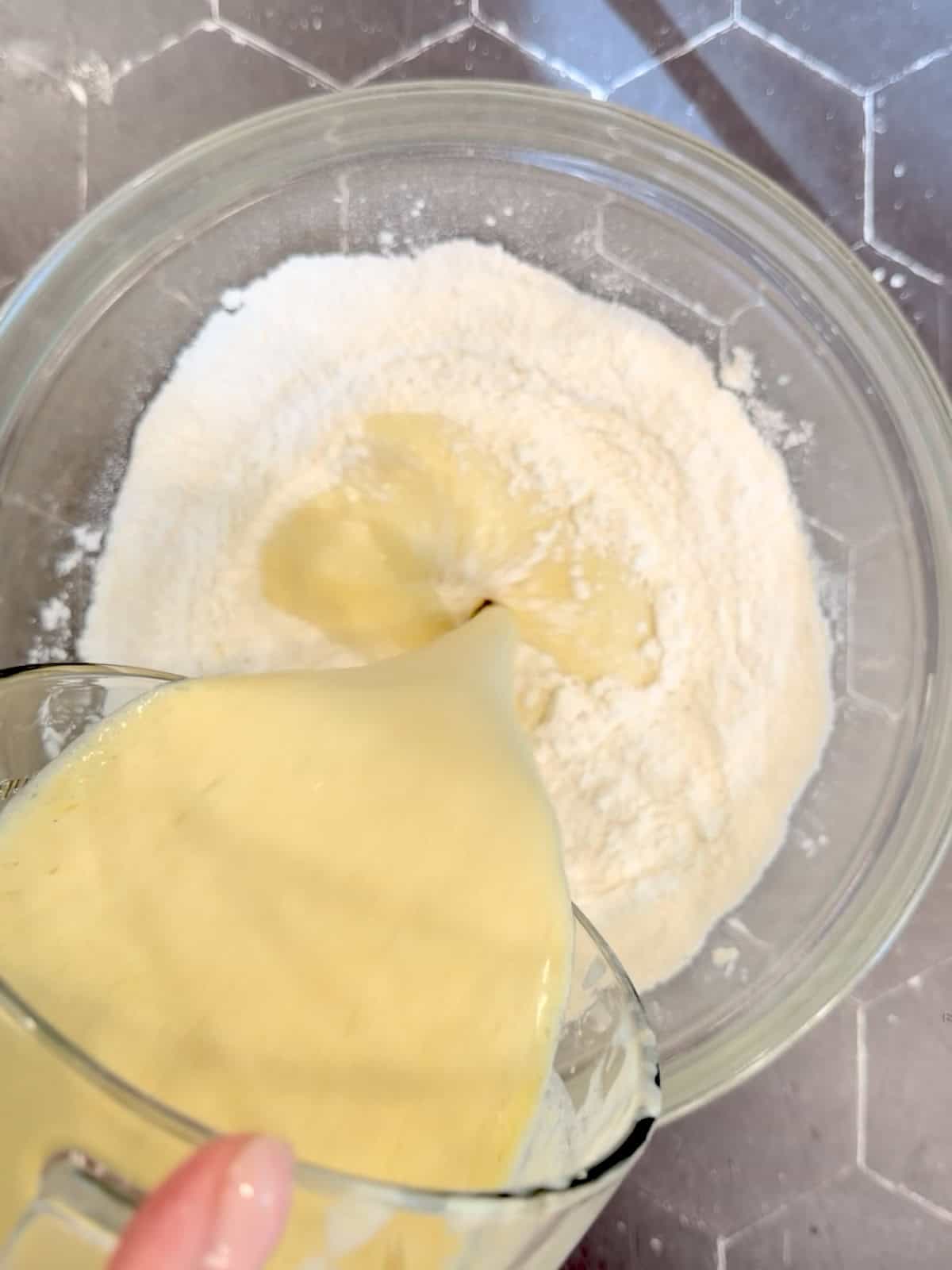 Adding wet ingredients to dry ingredients to make pancake batter.