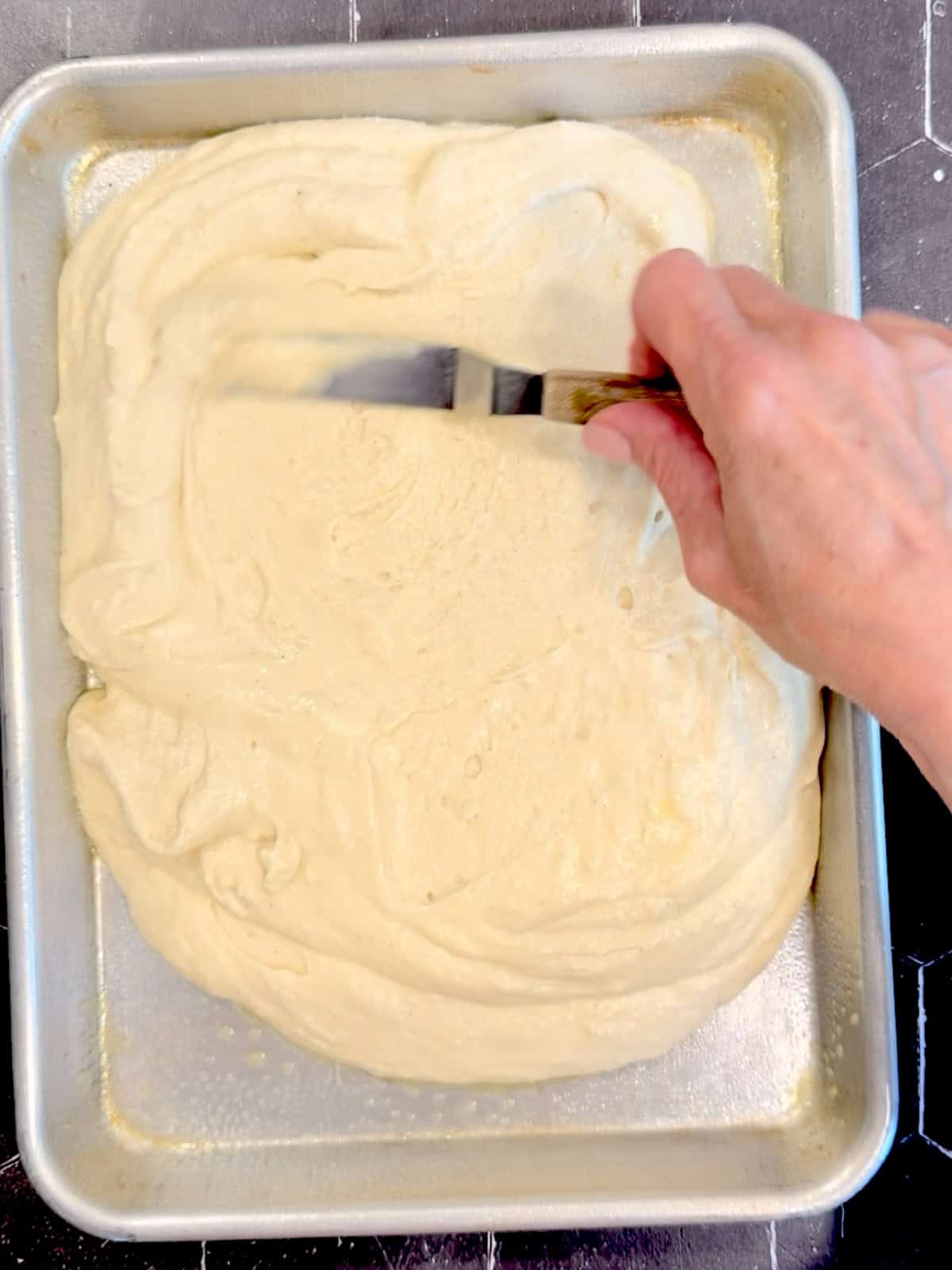 Spreading pancake batter in a quarter sheet pan.