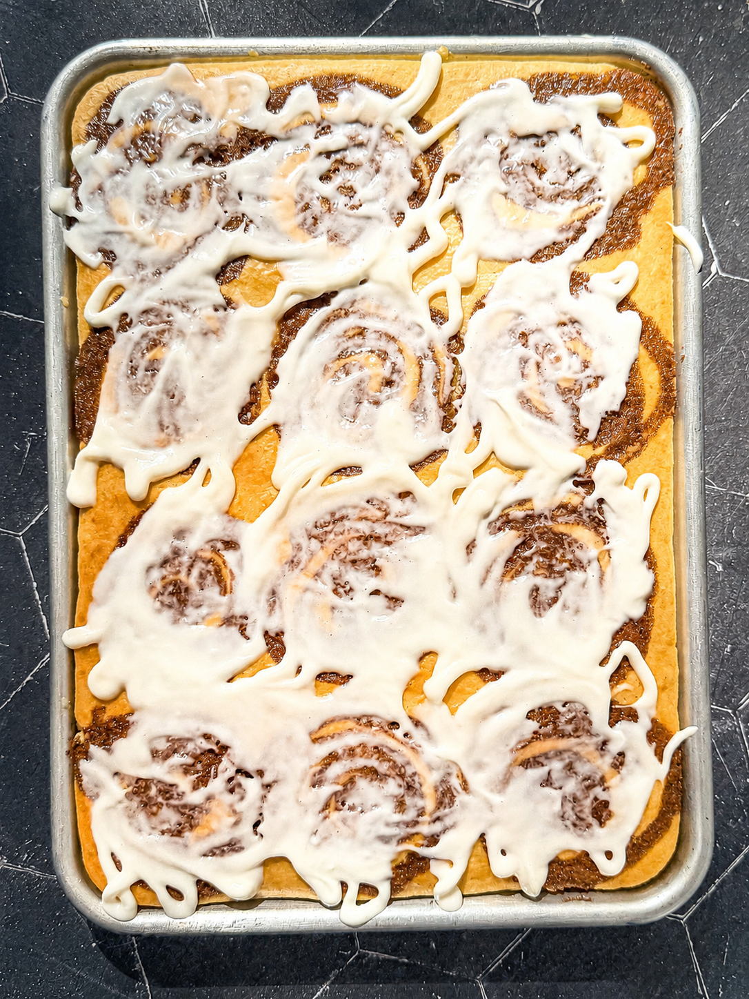 Cinnamon roll pancakes with cream cheese icing on a sheet pan.
