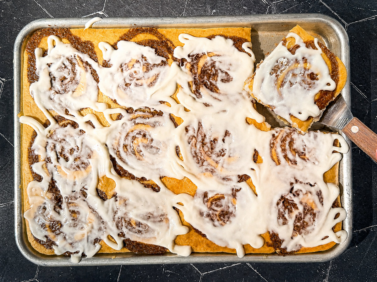 Cutting out a slice of sheet pan cinnamon roll pancakes.