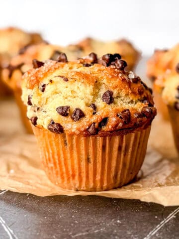 Chocolate chip Greek yogurt muffins on parchment paper on a black counter.