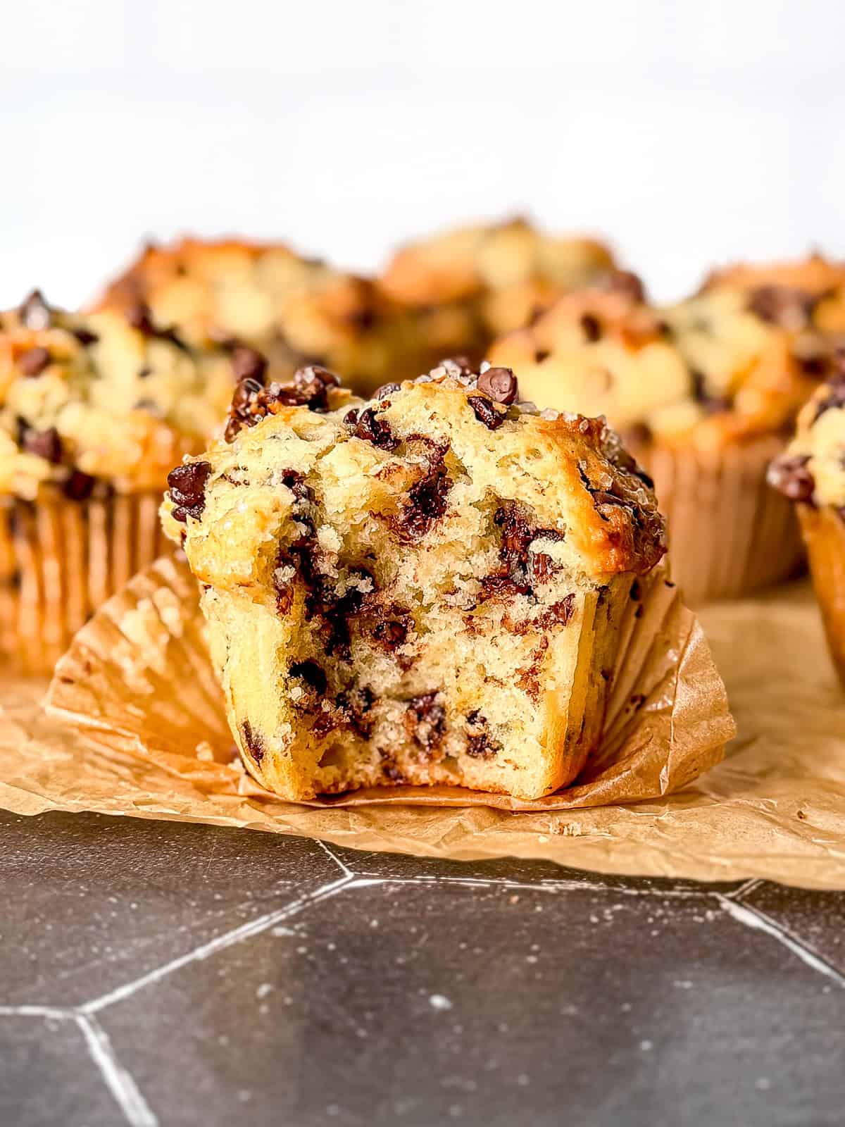 Chocolate chip Greek yogurt muffins on parchment paper on a black counter.