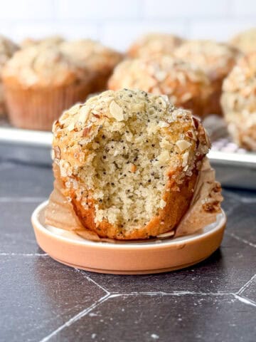 Side of view of an almond poppy seed muffin with a bite taken out.