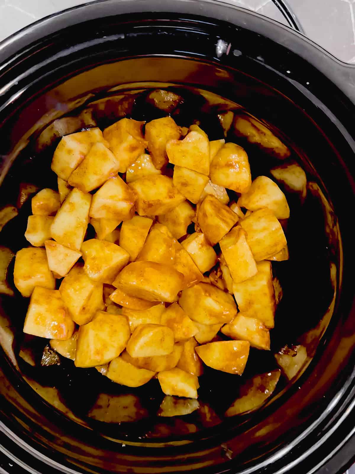 Spiced apples in the bottom of a slow cooker before cooking.