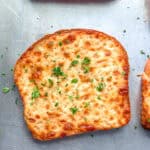 Pieces of cheesy toast on a sheet pan.