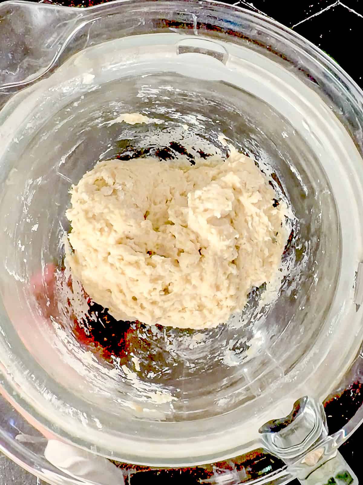 Donut dough after mixing by hand in a glass bowl.