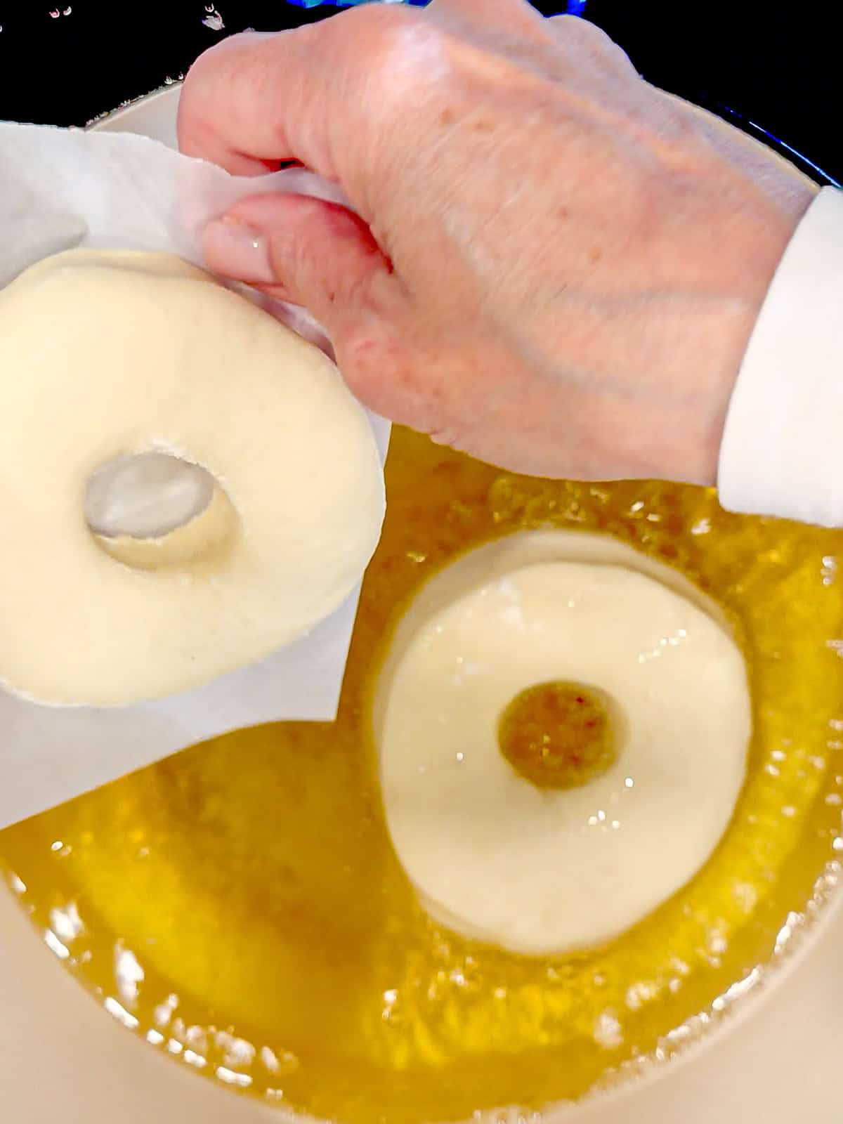 Using parchment paper to slip donuts into fryer oil.