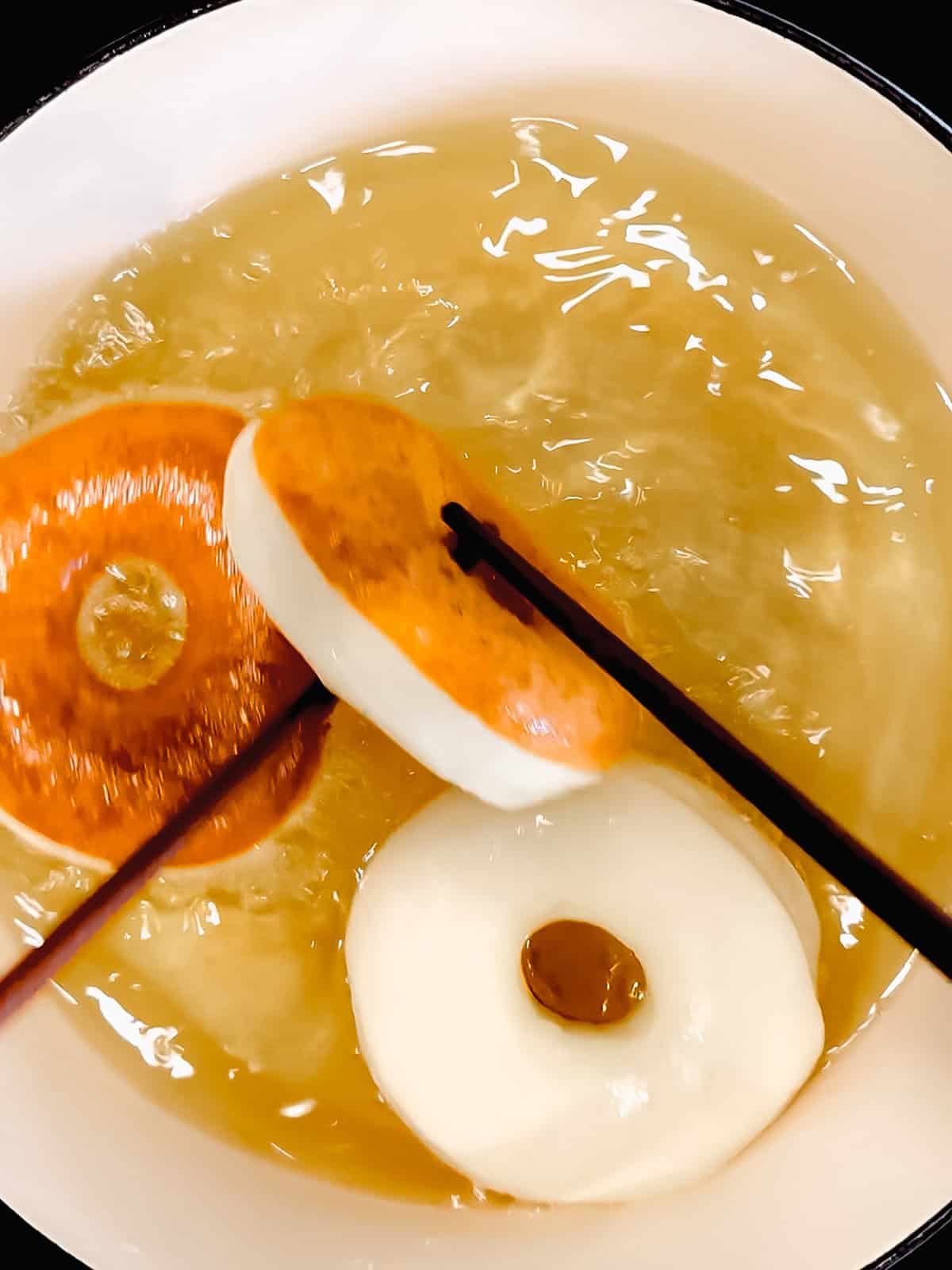 Using too long chopsticks to flip over donuts frying in oil.
