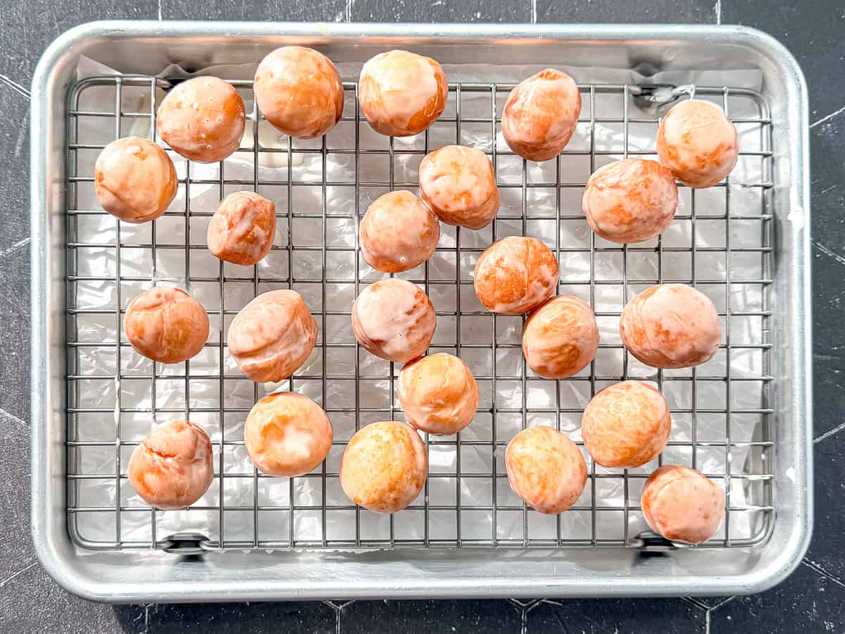 Donut holes on a wire rack on a sheet pan.
