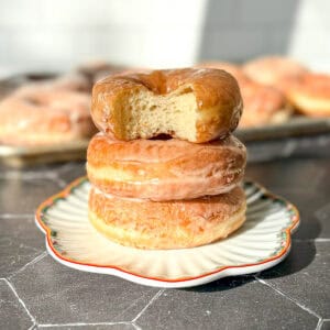A stack of donuts, the top one with a bite taken out.