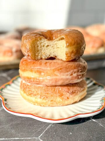 A stack of donuts, the top one with a bite taken out.